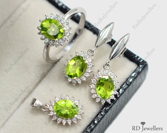 May include: A set of green peridot jewelry featuring a ring, a pendant, and a pair of earrings. Each piece has a green oval peridot stone surrounded by a halo of smaller white stones.