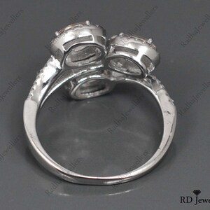 May include: A silver ring with two large, clear stones set in a twisted band. The ring is on a gray background.