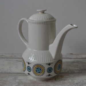 May include: White ceramic coffee pot with a blue and gold floral design around the base.