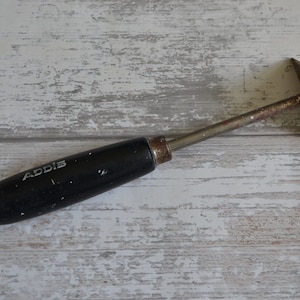 May include: A black handled putty knife with a metal blade. The handle has the word "ADDIS" printed on it.