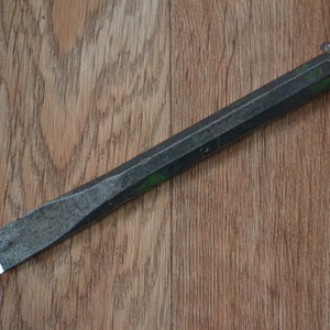 May include: A black metal chisel with a slightly rounded head and a hexagonal handle.