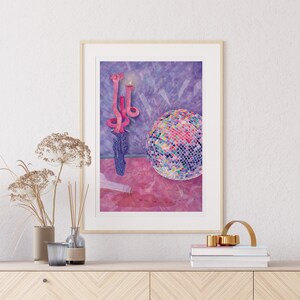 Puede incluir: Una pintura al agua enmarcada de una bola de discoteca rosa y un candelabro rosa con tres velas sobre un fondo morado.