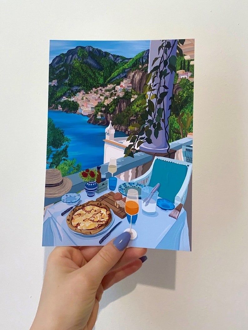 Puede incluir: Una pintura que representa una mesa puesta con una pizza, un vaso de zumo de naranja y una vista de una ciudad costera en el fondo. La mesa est&aacute; puesta con un mantel azul, platos blancos y cubiertos. La pizza est&aacute; cubierta de queso y tiene una corteza ligeramente quemada. El vaso de zumo de naranja est&aacute; medio lleno y tiene una pajita. La vista de la ciudad costera en el fondo muestra una serie de edificios en una ladera. El cielo es azul y hay nubes en el cielo.