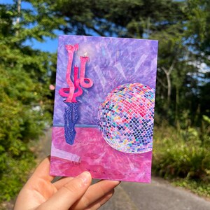 Puede incluir: Una ilustraci&oacute;n de una bola de discoteca, un candelabro y una botella sobre un suelo rosa y morado, en tonos rosa y morado.