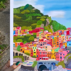 May include: A colourful illustration of a hillside village with buildings in shades of pink, yellow, blue, green, and red. The village is nestled against a green hillside with a blue sky above.