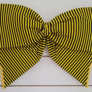 May include: A large yellow and black striped bow with a yellow crocheted trim. The bow is tied in a classic shape and is perfect for adding a touch of whimsy to any occasion.