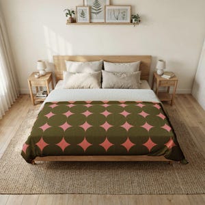 May include: A bedspread featuring a repeating geometric pattern of dark olive green circles and light pink four-pointed star shapes. The blanket covers a wooden bed frame with white pillows and a white sheet, set in a room with wooden nightstands.