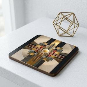 May include: Square coaster with a geometric design in gold, black, beige, and red. The coaster has a dark brown wooden edge. A gold geometric sculpture is in the background.