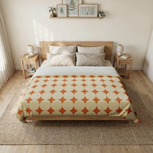 May include: A bed with a wooden frame and a patterned comforter. The comforter features a repeating design of large, cream-colored circles set against a burnt orange background. The bed is made up with pillows and a neutral-colored bed sheet.