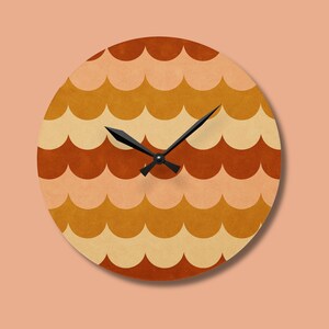 May include: Round wall clock with a retro design. The clock face features a repeating scallop pattern in shades of orange, tan, and cream. Black clock hands and a black center complete the design. The clock is a decorative home decor item.