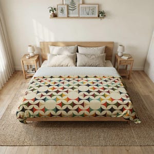 May include: A bed with a wooden frame and a colorful geometric patterned blanket. The blanket features a repeating design of circles and diamond shapes in shades of red, blue, green, and yellow. The room has wooden nightstands and a neutral color scheme.