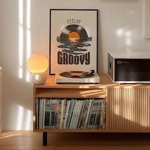 May include: A wooden record player stand with a record player, a lamp, and a framed print that says "Feelin' Groovy". The stand has a shelf for records and a drawer.