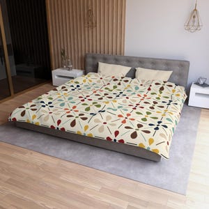 May include: A duvet cover featuring a repeating pattern of stylized flowers in shades of brown, red, yellow, blue, and green on a cream background. The design includes thin black lines connecting the floral motifs across the fabric surface.