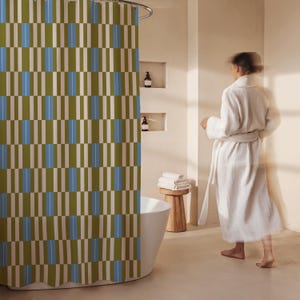 May include: A shower curtain featuring a repeating geometric pattern of vertical rectangular blocks in olive green, light blue, and white. The design consists of alternating columns of these colors, creating a structured, rhythmic visual effect.
