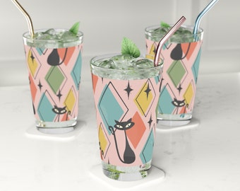 May include: Three clear glass tumblers with pink, yellow, blue, and green geometric patterns and black cat silhouettes. Each glass has a straw and ice cubes.