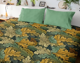 May include: A bed featuring a comforter with a dense, repeating pattern of oak leaves in shades of mustard yellow, sage green, and dark forest green. Two solid sage green rectangular pillowcases are placed at the head of the bed.