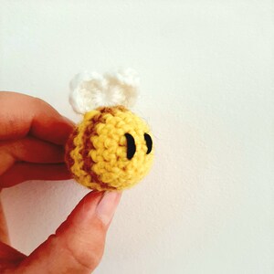 May include: A crocheted bee toy with yellow and brown stripes, white wings, and black eyes.