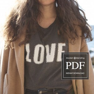 Puede incluir: Una camiseta gris con un gráfico blanco de "LOVE" cosido en la parte delantera. La camiseta la lleva una persona con el pelo largo castaño y un abrigo tostado. El texto "Modern Mending PDF INSTANT DOWNLOAD" es visible en la esquina inferior derecha de la imagen.