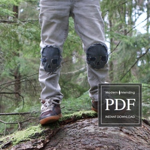 Puede incluir: Un par de pantalones vaqueros grises con parches de calavera negros en las rodillas. Los vaqueros los lleva una persona de pie sobre un tronco de árbol en un bosque. El texto "Modern Mending PDF INSTANT DOWNLOAD" es visible en la esquina inferior derecha de la imagen.