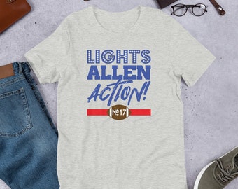Puede incluir: Camiseta gris claro con las palabras azules "LIGHTS ALLEN ACTION!". Tiene una franja roja y un gráfico de fútbol con el número "17". La camiseta está hecha de un material suave.