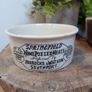 Może przedstawiać: Kremowy ceramiczny garnek z czarnym napisem Springfield Home Potted Meats, Prepared by Horrocks & Watson, Southport, oraz mniejszym tekstem wspominającym domowy ser cytrynowy, najlepszy miód i sos pomidorowy.