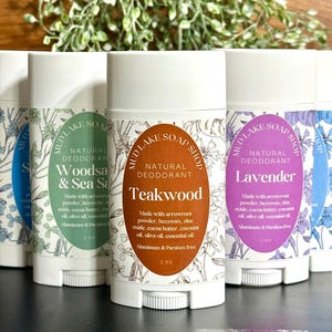May include: Several natural deodorants from Mud Lake Soap Shop are displayed. The labels feature the scents: Woods & Sea Salt, Teakwood, and Lavender. Each deodorant is in a white tube with a floral design and the text "Natural Deodorant".
