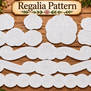 May include: A collection of white felt cutouts featuring embossed floral and paw print designs, arranged on a wooden surface. A rectangular sign at the top displays the text Regalia Pattern in black lettering with a small pink flower graphic.