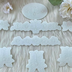 Pode incluir: Um conjunto de stencils de feltro branco com desenhos florais e de tulipas. Os stencils são perfeitos para artesanato e decoração.