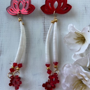 Può includere: Orecchini pendenti rossi e bianchi con un design a forma di fiore di loto. Gli orecchini presentano un fiore di loto rosso con un fiocco bianco e perline rosse.