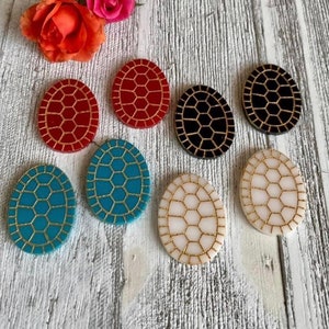 May include: Seven oval-shaped resin earrings with a turtle shell design. The earrings are in red, black, blue, and white with gold accents.