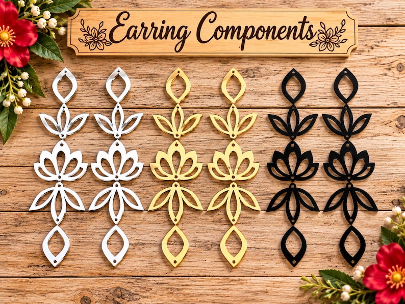 May include: Six vertical earring components arranged in pairs of silver, gold, and black. Each piece features a repeating cutout floral or leaf-like pattern with small holes for assembly. A wooden sign above reads Earring Components.