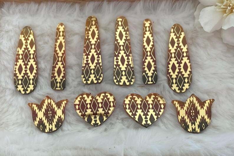 May include: A collection of ten decorative acrylic pieces featuring a reflective gold and dark brown geometric pattern. The set includes six elongated teardrop shapes and four smaller pieces consisting of two heart shapes and two tulip-like floral shapes.