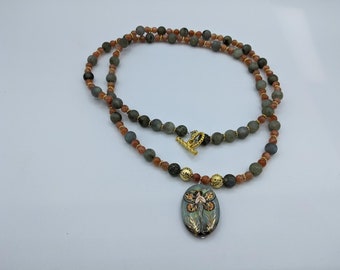This beautiful fairy bead is accented by Grey and orange beads with gold spacer beads and clasp.