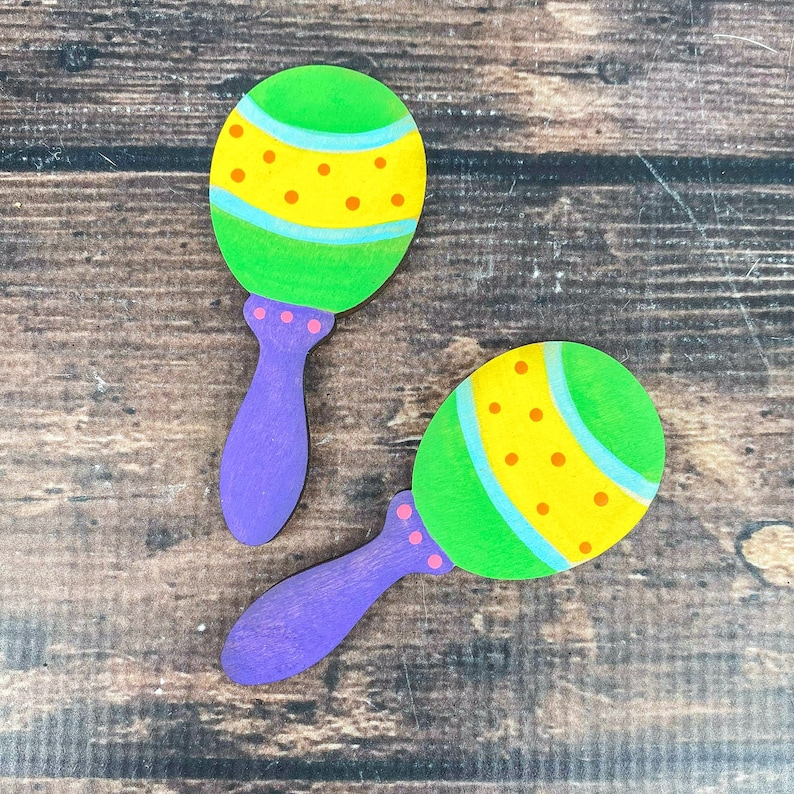 May include: Two wooden maracas with purple handles. The maracas are painted green, yellow, and orange with a pattern of dots and stripes.