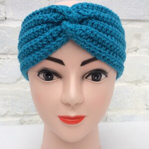 May include: A turquoise blue crocheted headband with a twisted knot design.