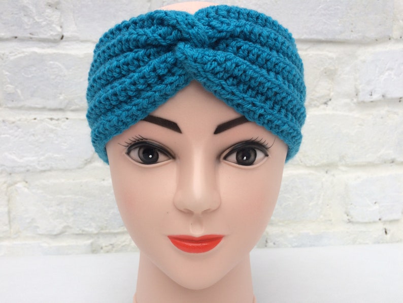 May include: A turquoise blue crocheted headband with a twisted knot design.