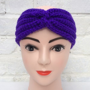 May include: Purple crocheted headband with a twisted knot design. The headband is worn on a mannequin head.
