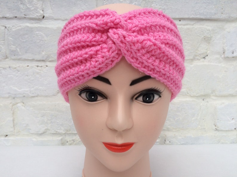 May include: A pink crocheted headband with a twisted knot design.