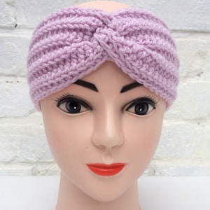 May include: A lavender crocheted headband with a twisted knot design. The headband is worn on a mannequin head.