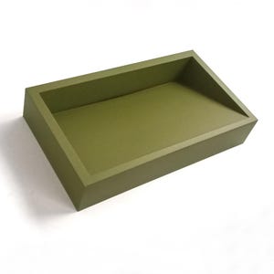 Può includere: Vassoio rettangolare verde oliva con lati angolati. Il vassoio è realizzato in un materiale solido e ha una finitura liscia e opaca. Il design è semplice e moderno, adatto a vari usi.