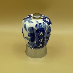 May include: A ceramic coffee maker with a white base and a blue floral design. The top is silver, and the base is a silver color. The coffee maker is a decorative item.
