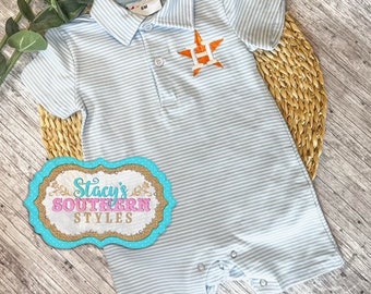 May include: A light blue and white striped baby onesie with a white polo collar and a small orange star with a white letter H on the front. The onesie has a snap closure at the bottom.