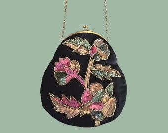 Può includere: Una borsa da sera in velluto nero con una tracolla a catena dorata e un motivo floreale realizzato con paillettes in tonalità rosa, verde e oro.