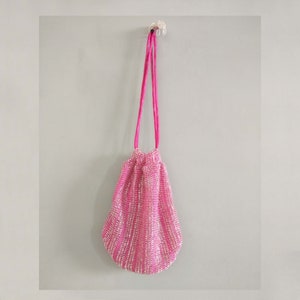 K&ouml;nnte beinhalten: Eine rosa paillettenbesetzte Kordeltasche mit einem rosa Satinband.