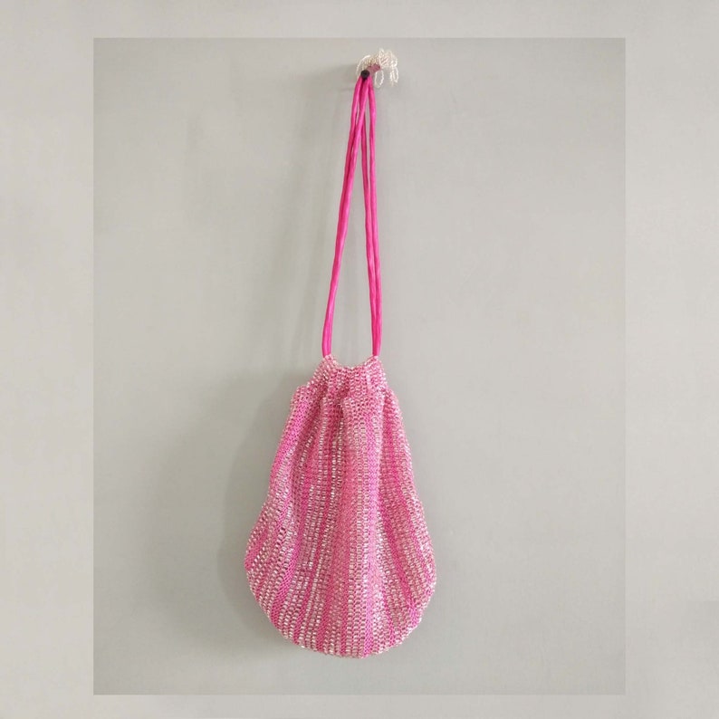 K&ouml;nnte beinhalten: Eine rosa paillettenbesetzte Kordeltasche mit einem rosa Satinband.