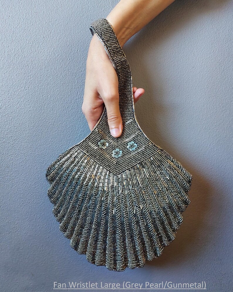 May include: A silver beaded fan-shaped wristlet with a beaded handle and a silver and blue floral design. The wristlet is large and has a grey pearl and gunmetal finish.