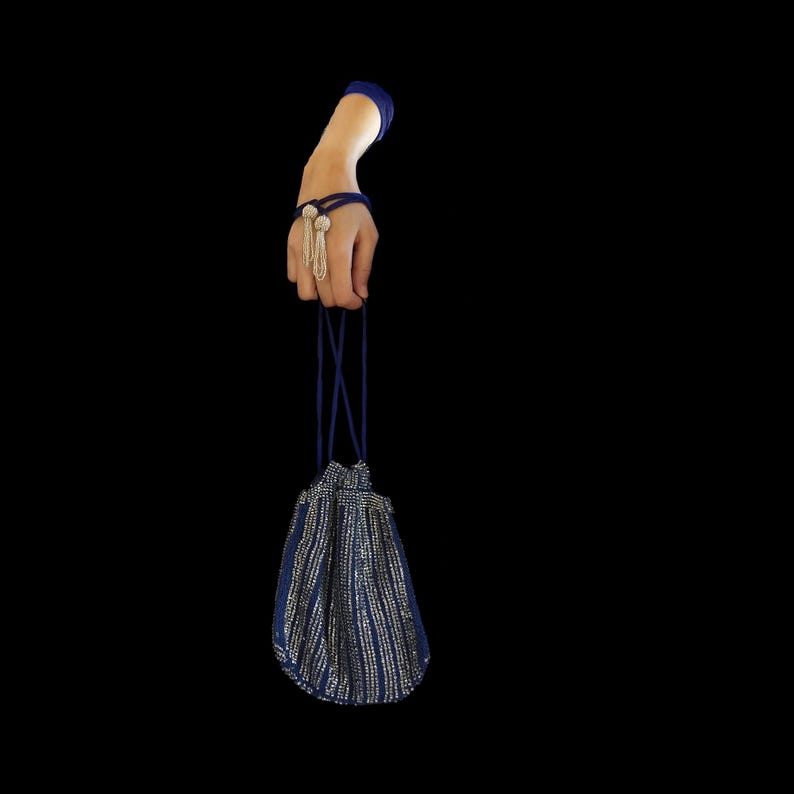 Puede incluir: Una bolsa de cord&oacute;n azul y plata con un asa de cord&oacute;n azul.