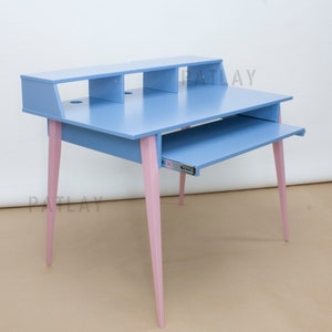 May include: A light blue desk with a pull-out keyboard tray and a shelf above. The desk has pink legs and the text "PATLAY" is printed on the side.