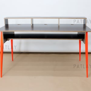 May include: A black desk with a shelf and two lower shelves. The desk has orange legs and the word "PATLAY" is printed on the side of the desk.