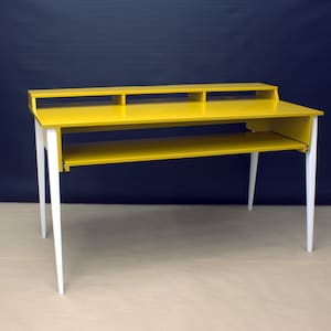 May include: A yellow desk with white legs and a shelf. The desk has a top shelf with two compartments.